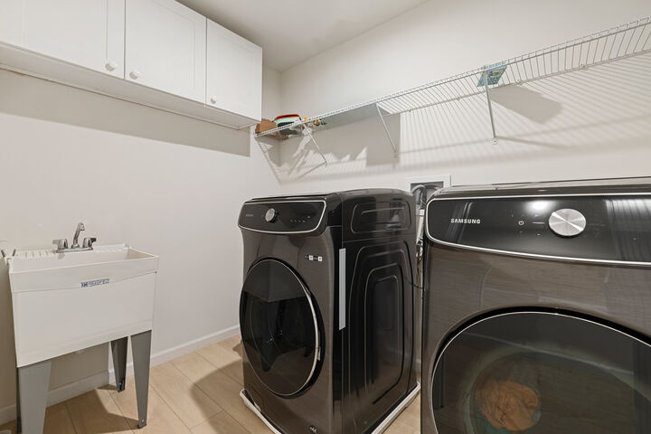 Second-floor laundry with a utility sink and cabinets.