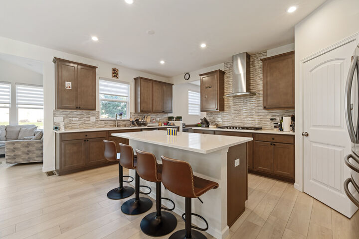 The island seats four; the cooktop sits under a chimney hood.